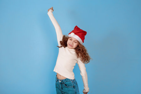 Yawning little African-American girl with Santa hat on blue background.の写真素材