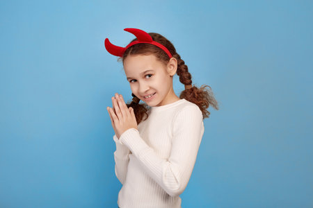 Tricky little African-American girl with decorative devil horns on blue background.の写真素材