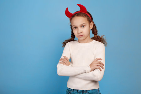 Confident little African-American girl with decorative devil horns on blue background.の写真素材