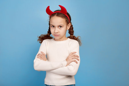 Confident little African-American girl with decorative devil horns on blue background.の写真素材
