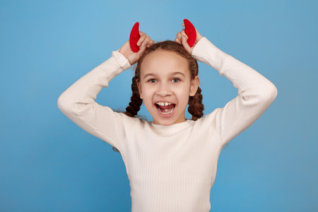 Happy little African-American girl with decorative devil horns on blue background.の写真素材