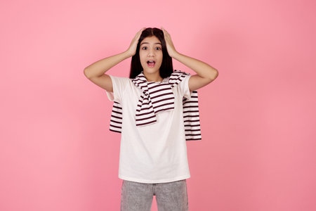 Young shocked teenage girl on pink background in studio.の写真素材