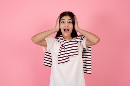 Young shocked teenage girl on pink background in studio.の写真素材