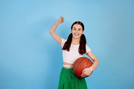Young brunette teenage girl with basket ball and ponytails on blue background.の写真素材