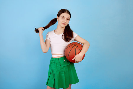 Young brunette teenage girl with basket ball and ponytails on blue background.の写真素材