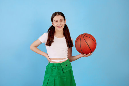 Young brunette teenage girl with basket ball and ponytails on blue background.の写真素材