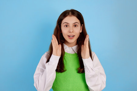 Young brunette teenage girl surprised on blue background.の写真素材