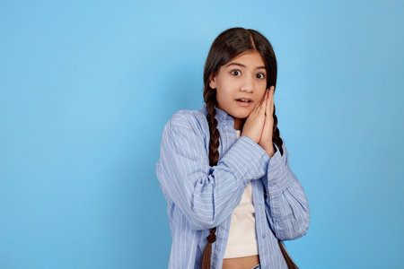 Frightened teenage girl in blue shirt on blue background.の写真素材
