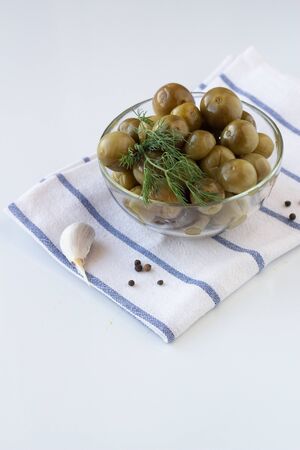 Sour green cherry tomatoes with dill in a glass plate on a white towel on a white background. Trending Fermented Vegetablesの写真素材