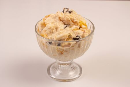 Salad of apple, orange, oat hops and prunes with honey in a glass plate on a white background. Vegetarian dietの写真素材