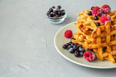 Carrot waffles with prunes, walnuts, cinnamon, ginger and nutmeg on a gray plate on a grey...