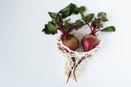 Two Fresh raw beets with tops in an eco bag close-up on a white background. Vegetarian and raw food dietの写真素材