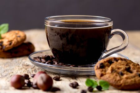Black coffee in a glass cup with coffee beans. near cookies and hazelnutsの写真素材