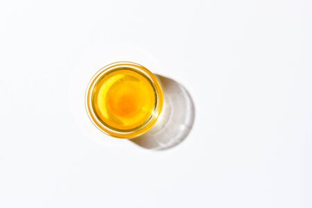 Honey in a small glass plate on a white background top view. Nearby lies a wooden spoon. High quality photoの写真素材