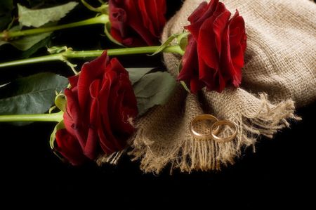 Wedding rings and roses on bagging. Isolated on black. Glamour styled.の写真素材