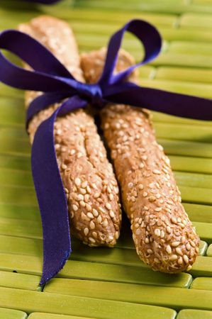 Close-up of sesame breadsticks tied with purple ribbon の写真素材