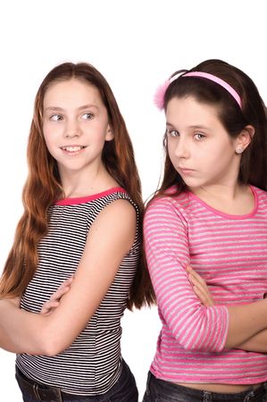 Two girls in the age of ten and eleven standing hands crossed isolated on whiteの写真素材