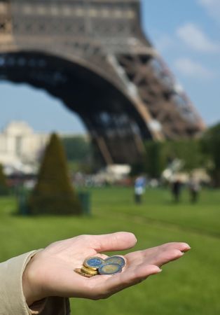Euro coins on the mature woman hand with eiffel tower on backgroundの写真素材