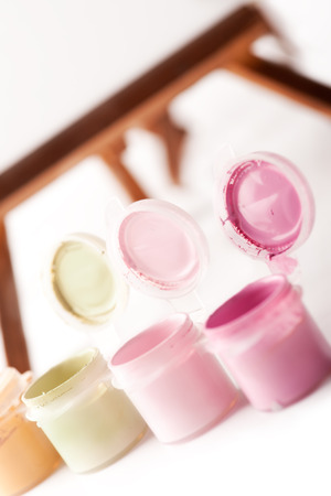 Small pots of acrylic paint with wooden easel on backgroundの写真素材