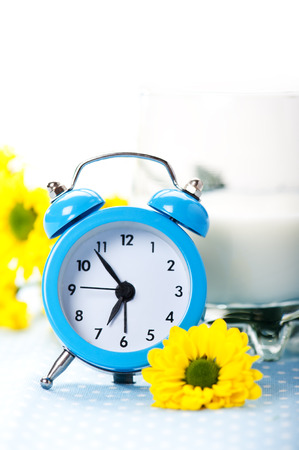 Blue alarm clock with milk and yellow flowersの写真素材