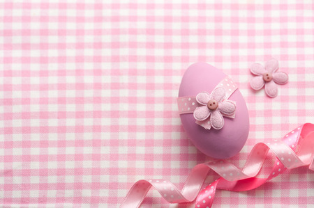 Pink egg with flowers and ribbon on napkinの写真素材