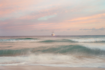 Seascape dawn with ship and pink dreamy waters and sky. Long exposureの写真素材
