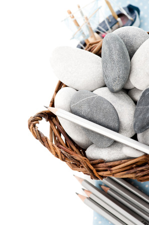 Wicker bascket with sea stones, pencils and toy boatの写真素材