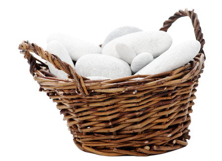 Wicker bascket with sea stones isolated on whiteの写真素材