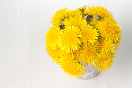 Dandelions in a basket on white wooden background の写真素材