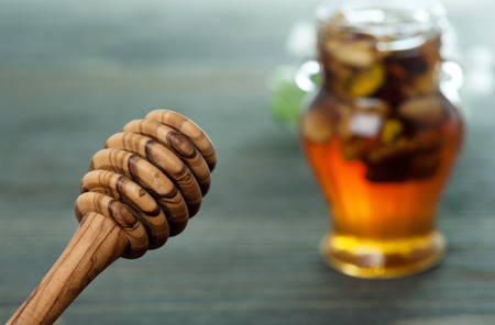 Honey spoon and jar with different nuts on a dark wooden table backgroundの写真素材