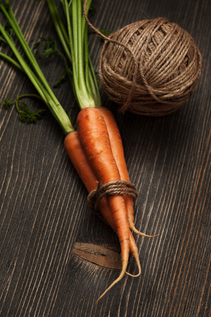 Still life with raw carrots on dark wooden table and twineの写真素材