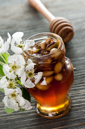 Honey in a jar with different nuts on a dark wooden tableの写真素材