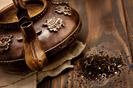 Antique iron hot tea pot and tea leaves on dark wooden backgroundの写真素材