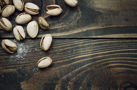 Closeup of pistachios nuts and salt on dark brown wooden tableの写真素材
