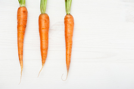 Three raw carrots on white wooden table. Food backgroundの写真素材