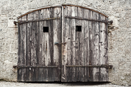 Old wooden barn door with damaged rusty stone wallの写真素材