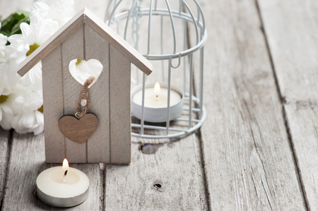 Easter festive background with lit candles, flowers and birdhouseの写真素材