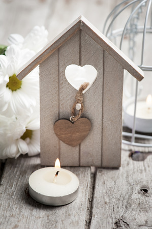 Easter festive background with lit candle, flowers and birdhouseの写真素材