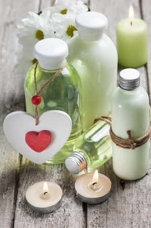 SPA still life, bath products, lit candles, wooden background, green grey, red heartの写真素材