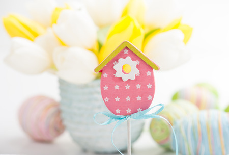 Pink Wooden Toy Bird House, Easter decoration. Tulips and easter eggs on backgroundの写真素材