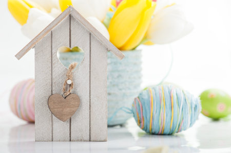 Easter decoration with eggs, bird house and tulip flowers