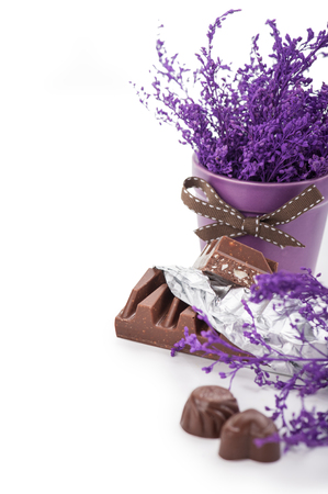 Still life with chocolate bar in foil, chocolates and pot flowerの写真素材