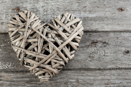 Background with wicker decorative heart on weathered wooden planks. Place for text.の写真素材