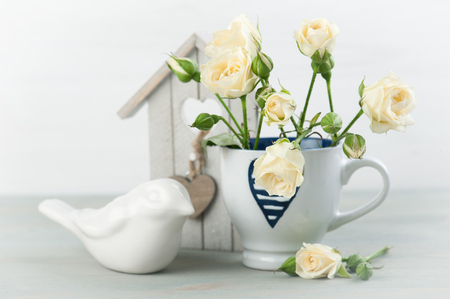 Vintage still life. Bouquet of white roses, wooden background and bird house, vintage decor.の写真素材
