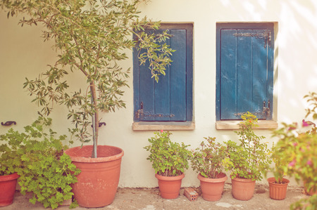 Blue wooden windows, flower pots in the medieval cretan town. Toned imageの写真素材