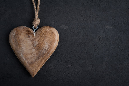 Black concrete background with wooden heart, place for chalk textの写真素材