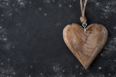 Black concrete background with wooden heart, place for chalk text. Snow and starsの写真素材