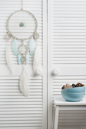 Dream catcher with mint feathers in the interior with blue bowlsの写真素材