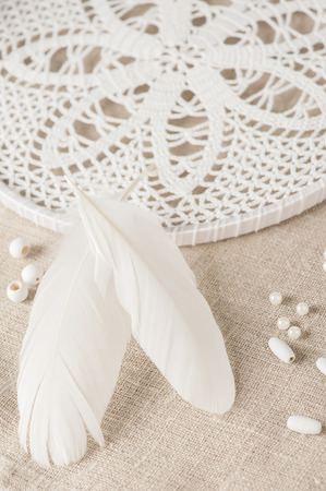 Close-up of feathers and white dream catcher. Handmade workshop composition of beads, threads, tools for DIYの写真素材