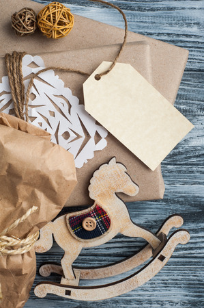Flat lay background with christmas gift, feathers, tag and decoration on wooden background. Craft wrapping. View from aboveの写真素材